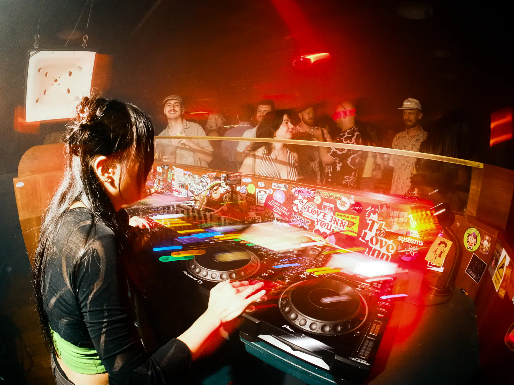 붉은 조명 아래 부스에서 음악을 트는 DJ